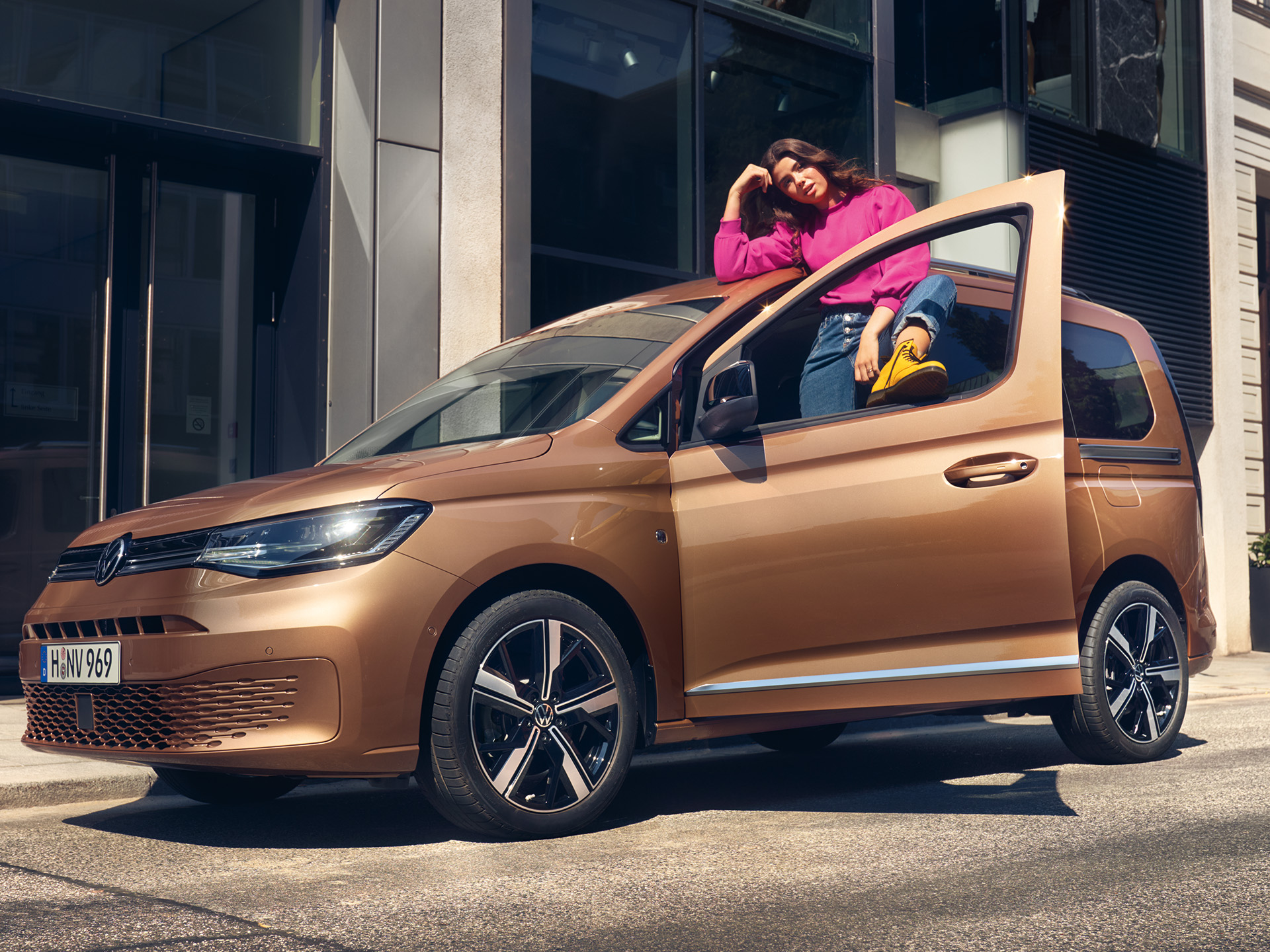 Eine Person steht in der Tür eines VW Caddy welcher in der Innenstadt parkt.
